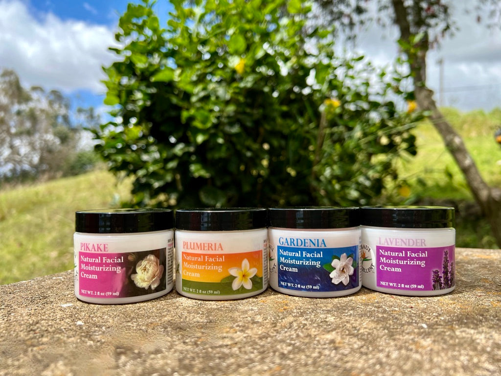 All Maui Excellent Moisturizing Creams on a cement table with a small tree, blue sky, and clouds in the background.