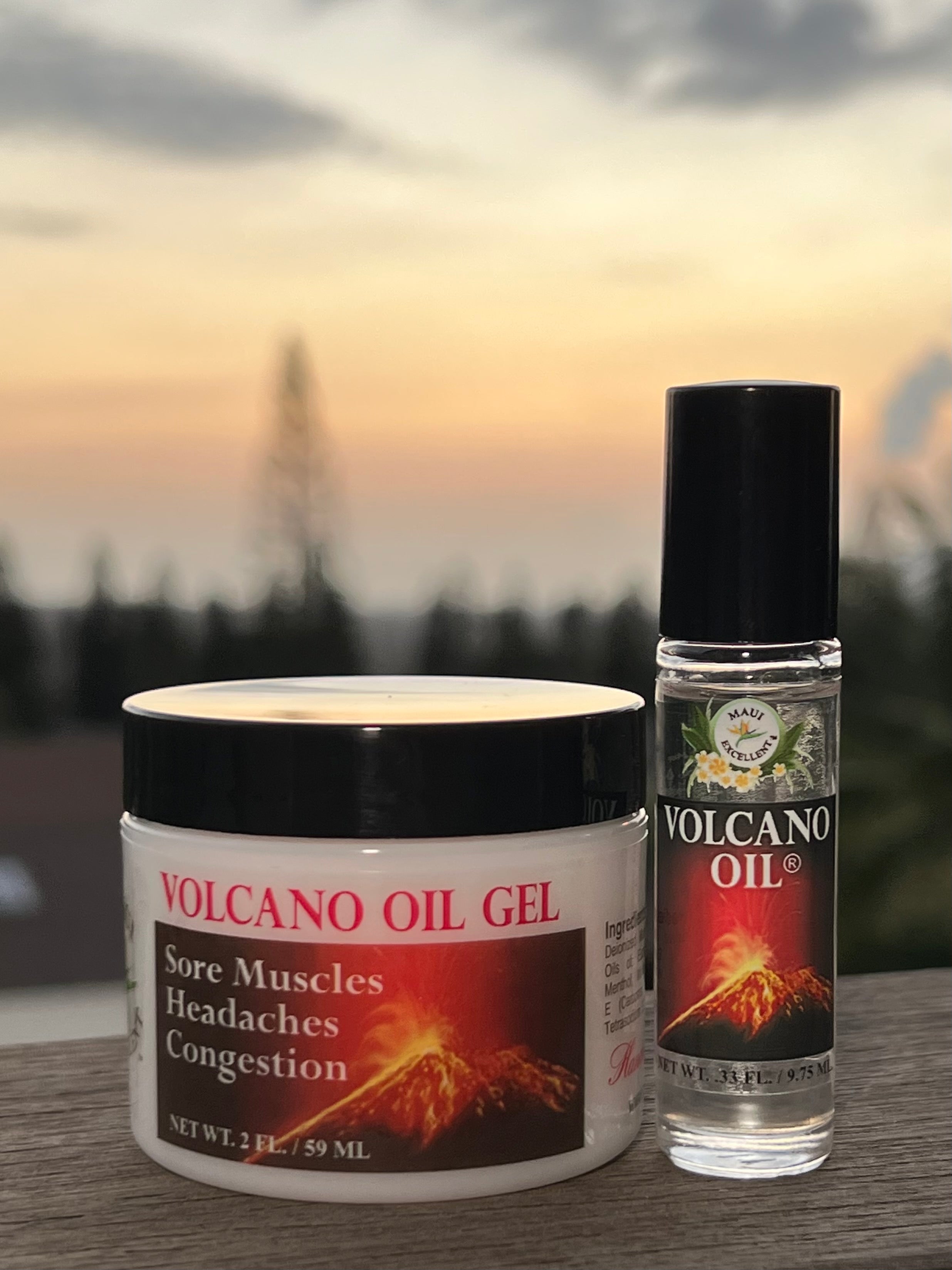 Maui Excellent Volcano Oil Gel and Volcano Oil Roll-on in foreground with sunset and tree silhouettes in the background.